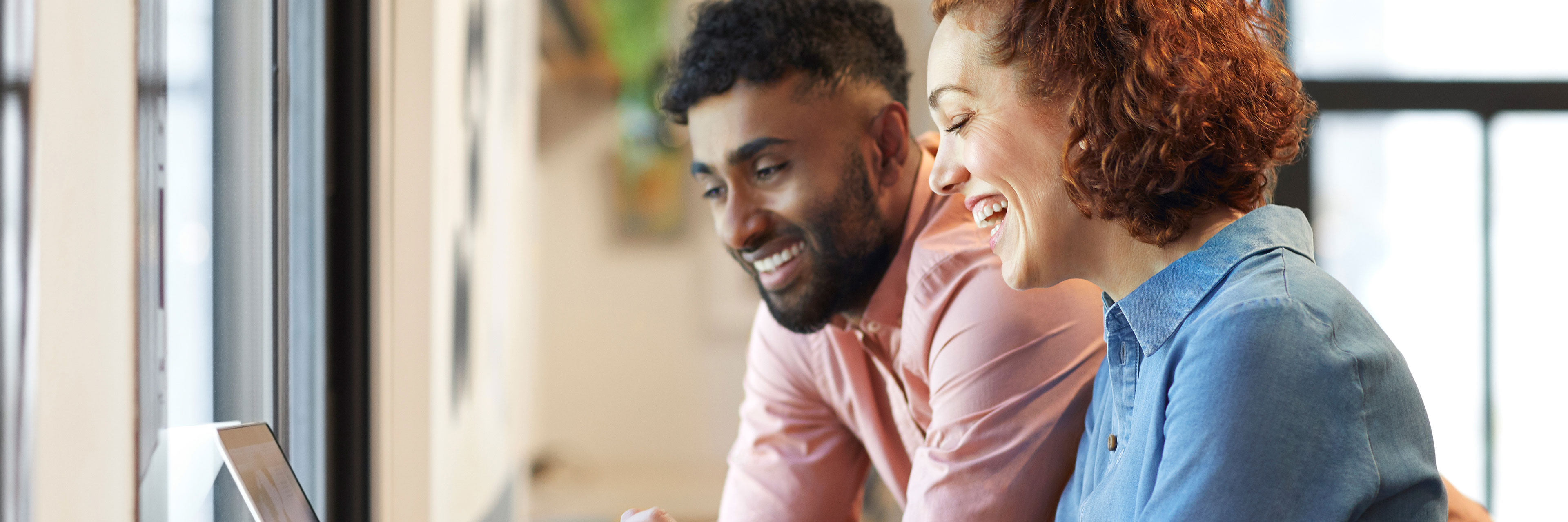 Close-up of woman and man smiling in front of laptop